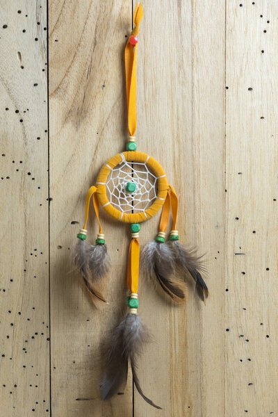 orange dreamcatcher on wooden wall 