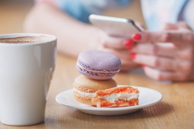 Fransızca macarons plaka ve bir fincan kahve, yumuşak odak arka plan üzerinde renkli