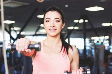 Spor salonunda, yumuşak odak arka plan elinde dumbbells ile sportif genç kadın