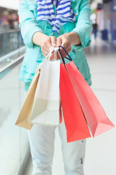 Beautiful pregnant woman with paper packages in the mall, soft focus background