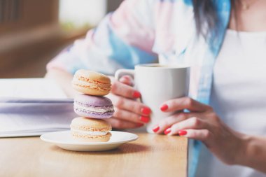 Bir fincan kahve ve macarons, yumuşak odak arka plan ile el