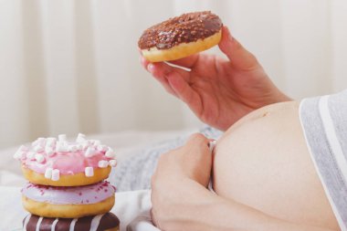 Plaka, yumuşak odak arka plan üzerinde farklı çörek ile hamile kadın