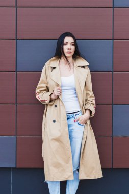 Bej bir palto ve kot sokak, yumuşak odak arka plan üzerinde güzel kadın
