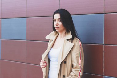 Bej bir palto ve kot sokak, yumuşak odak arka plan üzerinde güzel kadın