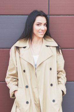 Bej bir palto ve kot sokak, yumuşak odak arka plan üzerinde güzel kadın