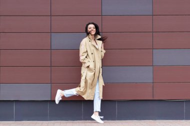 Bej bir palto ve kot sokak, yumuşak odak arka plan üzerinde güzel kadın