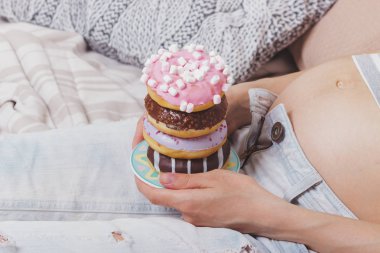 Farklı renkli çörek ve çay, yumuşak odak arka plan ile hamile kadın