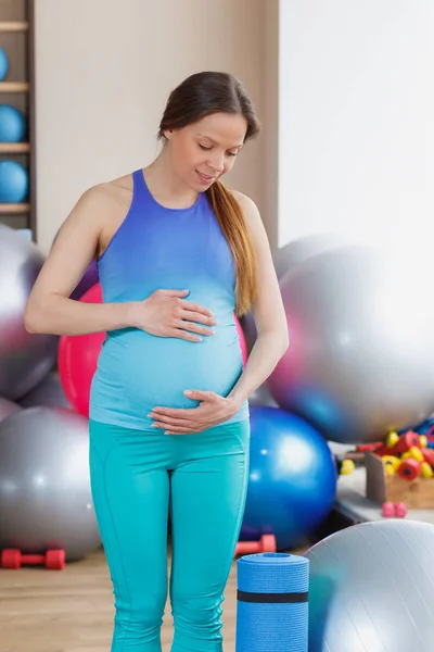 Pregnant woman with a mat in the gym. soft focus