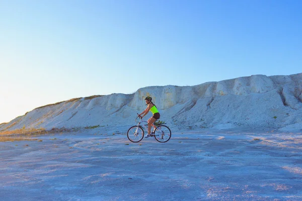 Young sporty woman with a bike on a sunset, soft focus background