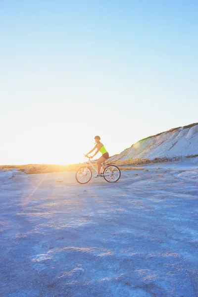 年轻的女运动员 日落时骑自行车 背景柔和 — 图库照片