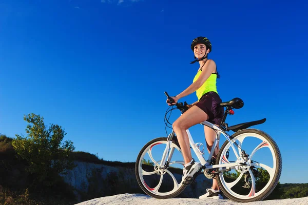 Young sporty woman with a bike on a sunset, soft focus background