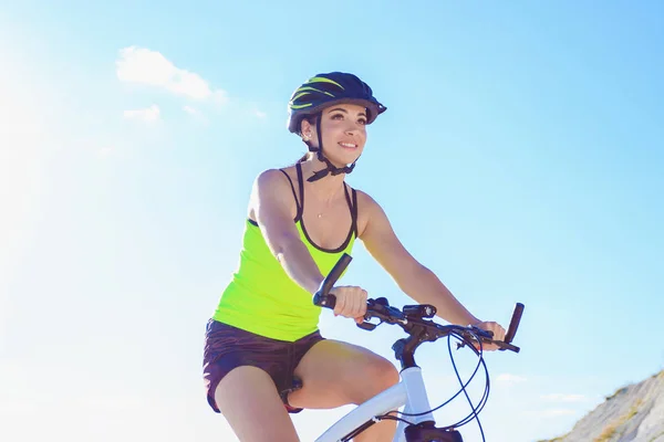 Günbatımında bisikleti olan genç bir kadın, yumuşak odaklı arka plan.