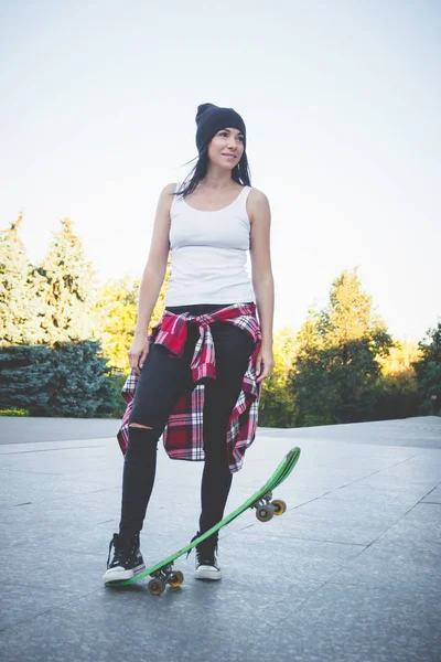 Beautiful woman with a skateboard on the street, soft focus background