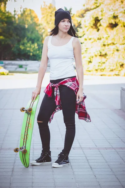 穿着衬衫和牛仔裤的美丽女人在街上骑着滑板 — 图库照片
