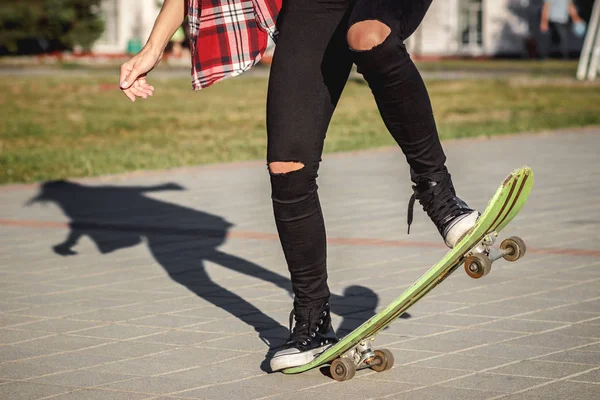 穿着衬衫和牛仔裤的美丽女人在街上骑着滑板 — 图库照片