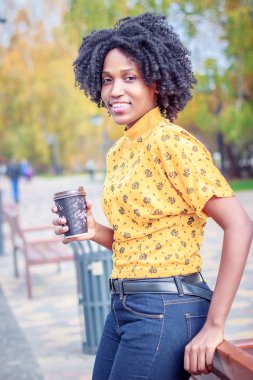 Kahve fincan sıcak içecek, holding rahat kıyafetler giymiş genç esmer kadının