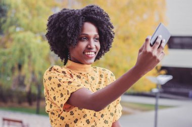 Genç gülümseyen rahat kıyafetler giymiş esmer kadın onun telefonu, arka plan bulanık bir fotoğraf yapmak