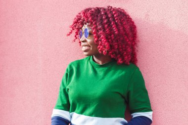 Sevimli genç Afrikalı kadın mavi güneş gözlüğü. Moda ve şık bir kız pembe duvara yakın, yumuşak odak arka plan poz