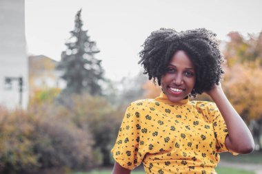 Esmer genç gülümseyen kadın rahat kıyafetler giymiş, arka plan bulanık