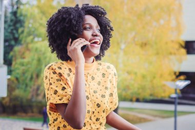 Genç gülümseyen kadın koyu renkli arka plan bulanık onu telefonla konuşurken rahat kıyafetler giymiş