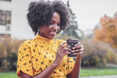 Kahve fincan sıcak içecek, holding rahat kıyafetler giymiş genç esmer kadının