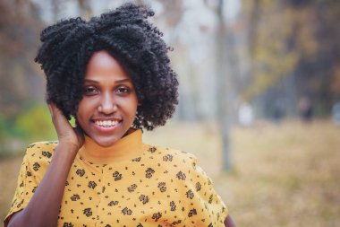 Esmer genç gülümseyen kadın rahat kıyafetler giymiş, arka plan bulanık