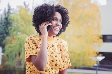 Genç gülümseyen kadın koyu renkli arka plan bulanık onu telefonla konuşurken rahat kıyafetler giymiş