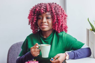 Giyimli kadın esmer sıcak içecek fincan tutarak rahat kıyafetler içinde zevk kahve veya çay, yumuşak odak arka plan