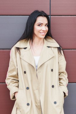 Bej bir palto ve kot sokak, yumuşak odak arka plan üzerinde güzel kadın