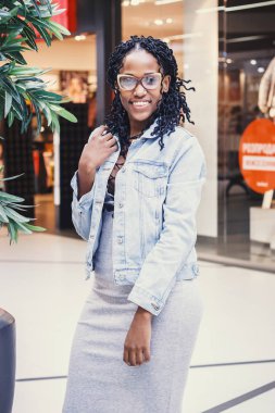 Genç esmer kadın alışveriş merkezinde rahat kıyafetler giymiş, arka plan bulanık