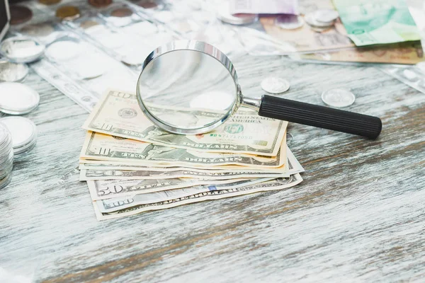 Diferentes monedas de colección en la caja, billetes y lupa — Foto de Stock