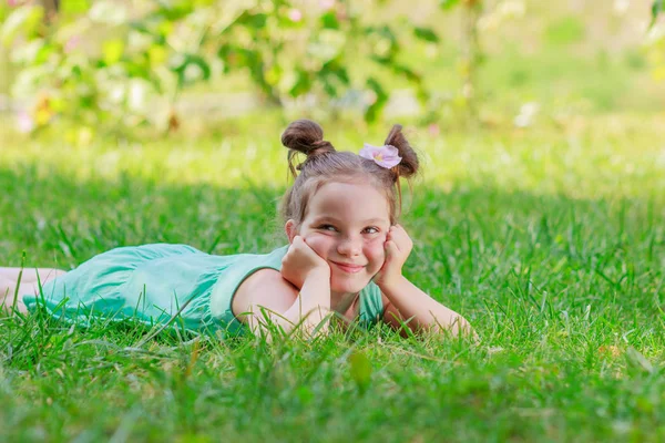 Cute girl lying on the green grass, outdoors, summer time, blurred background Royalty Free Stock Photos