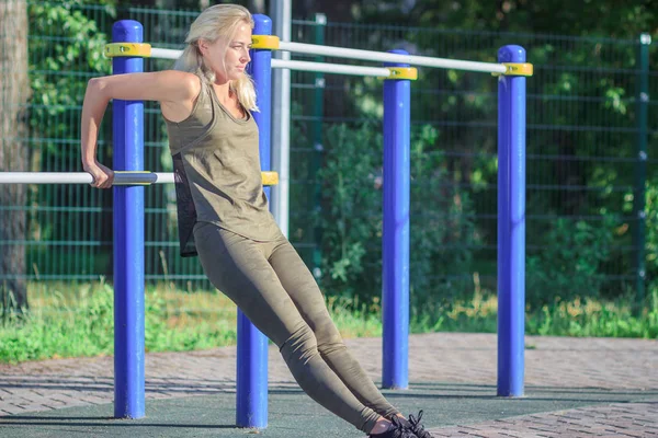 Mulher bonita faz exercícios esportivos no chão do esporte, fundo embaçado — Fotografia de Stock