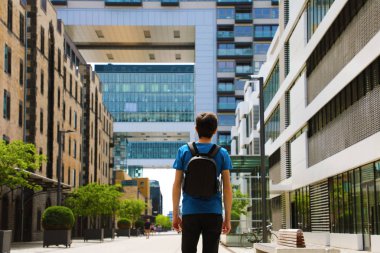 Arkadan Görünüş sırt çantası ile genç bir adam geldi büyük şehir ve seyir bakış açıları ve fırsatlar, Köln şehir semtinde, Almanya ile modern binalar için