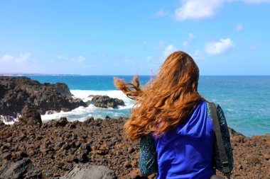 Los Hervideros, okyanus Lanzarote adasında rüzgarlı bölge yürüyüş uzun yürüyüşe çıkan kimse erkek. Genç kadının volkanik kanarya adada, İspanya hiking arkadan görünüm.