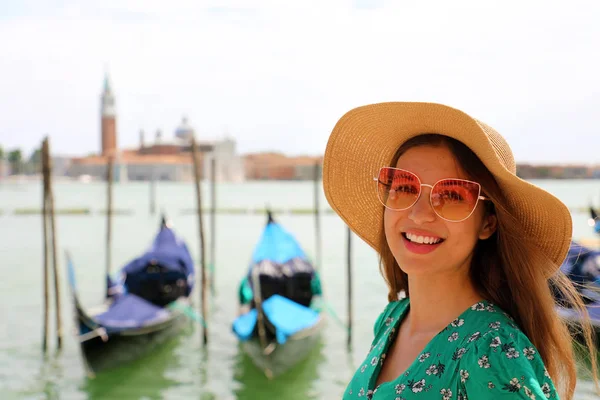 Gülümseyen kadın güneş gözlüğü ve şapka kameraya Venedik Lagünü ile arka planı arıyorum.