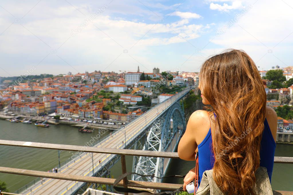 Attractive female tourist enjoying cityscape of Porto City with the famous bridge Dom Lus I on the river Douro. Back view of young traveler woman in Porto, Portugal.
