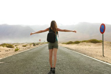 Özgürlük ücretsiz mutluluk mutluluk boş asfalt çöl yol kadında uçan. Sessizlik içinde çöl yol seyahat sırasında zevk mutlu kadın traveler backpacker Lanzarote tatil tatil. Düşük açılı.