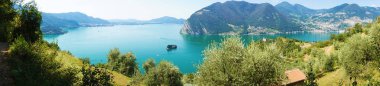 Panoramic view of mountain lake with island in the middle. Panorama from Monte Isola Island with Lake Iseo. Italian landscape. Island on lake. View from the island Monte Isola on Lake Iseo, Italy. clipart