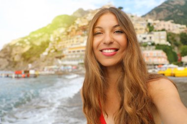 Amalfi Coast, İtalya Positano köyde çekici genç kadın portresi. Positano köyü arka planda olan sarışın gülümseyen bikini kız. Yaz tatili. Güneş ışığı flare vintage filtre.