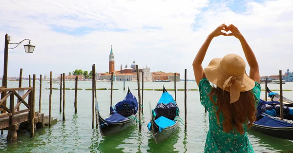 Woman making heart shape with hands on the beautiful view of Venice Lagoon, Italy