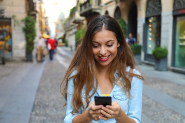 Milan şehir arka planda sokak ile akıllı telefon mesajlaşma güzel ve genç birbayan. Güzel kız akıllı telefon sohbet.