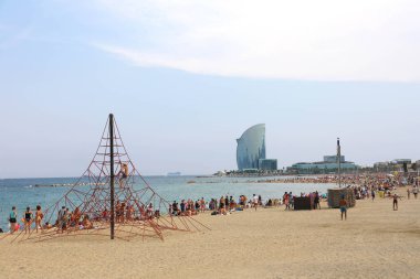 BARCELONA, SPAIN - JULY 11, 2018: amazing view of Barceloneta beach with people enjoying sunny day in Barcelona and W hotel on background, Catalonia, Spain clipart