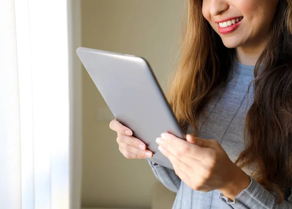 Young cheerful woman holding tablet at home, focus on the tablet