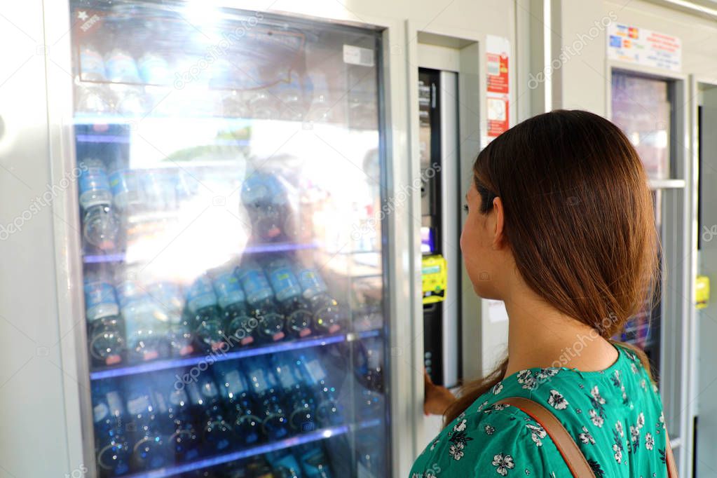 Young female backpacker tourist choosing a snack or drink at vending machine in Venice, Italy. Vending machine with girl.