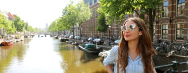 Güzel neşeli modeli güneş gözlüğü tarafına bir tipik Amsterdam kanalları, Hollanda üzerinde seyir ile portresi. Panoramik afiş görünümü.