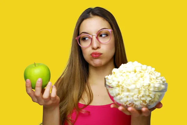 Woman choosing between unhealthy bowl of pop corn and an healthy