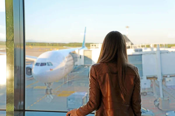 Mladá žena na letišti se dívá oknem na airplan — Stock fotografie