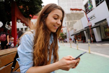 Sao Paulo City, Brezilya cep telefonu ile sokak bankında mesajlaşma oturan güzel öğrenci kız