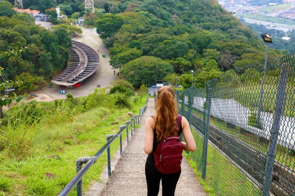 Ung turist flicka som bär ryggsäck fallande trappor och njuta av utsikten från Jaragua Peak, Brasilien — Stockfoto